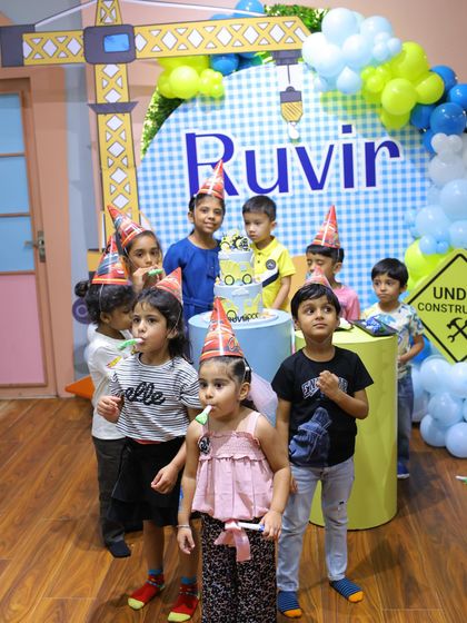 The cake-cutting ceremony at the construction-themed party. The kids, wearing cute construction hats, gather around for the big moment.