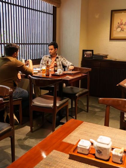 Guests enjoying a quiet conversation and a meal. Our space is designed for both intimate dinners and friendly gatherings, offering a comfortable and traditional setting.