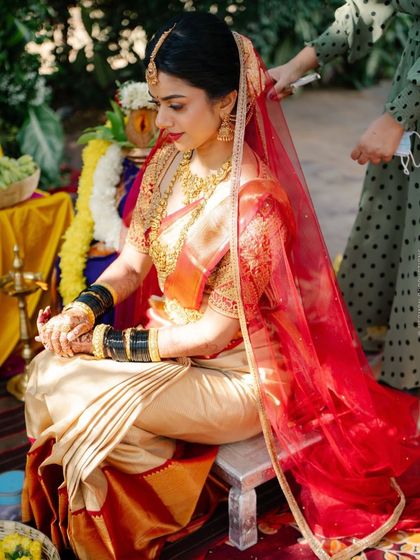 Bride Supriya during her muhurtham ceremony, wearing an off-white Kanchivaram saree with her custom red embroidered blouse and a sheer red veil.