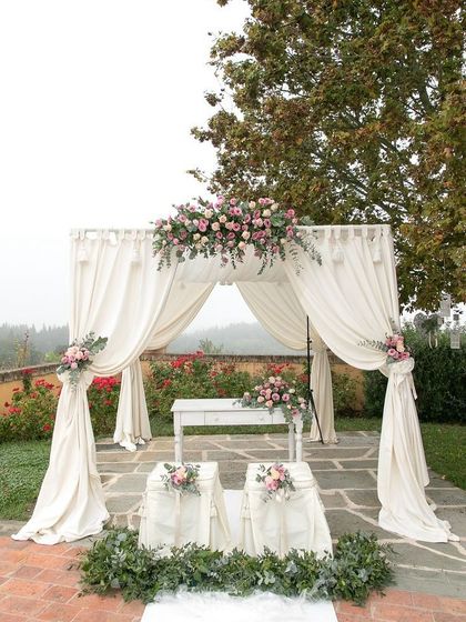 A rustic and romantic wedding mandap with off-white drapes and pastel pink floral arrangements. This setup is perfect for an intimate garden or farmhouse wedding.