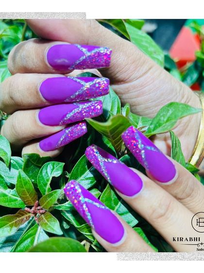 Another view of the dramatic matte purple and glitter nail extensions, showing off their length and coffin shape.