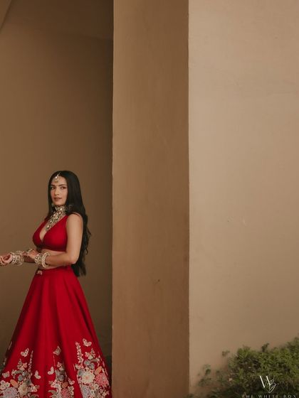 A candid shot showing the beautiful details of Shubhangi's red lehenga and her fresh, dewy makeup.