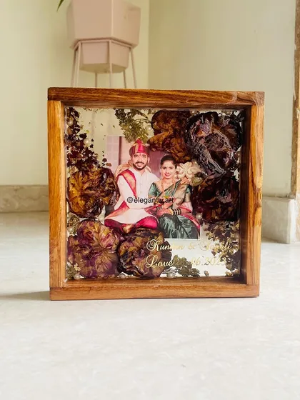 This square teakwood frame is a beautiful example of how I can preserve your wedding garland. The flowers are artfully arranged around the couple's photo, creating a timeless piece of home decor.