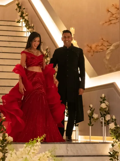 Making their grand reception entrance. The dramatic ruffles of the bride's Gaurav Gupta gown and the sharp tailoring of the groom's Shantanu & Nikhil outfit create a powerful, high-fashion statement.