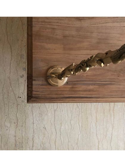 The intricate brass chain of the indoor swing, anchored to a wooden base. This detail highlights the fusion of traditional materials like brass with the clean lines of contemporary interior design.