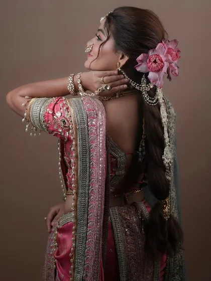 A back view showcasing the beautiful braided hairstyle adorned with a fresh lotus flower, a perfect complement to the traditional attire.