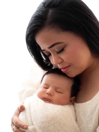 A close-up of comedian Bharti Singh holding her sleeping newborn. This shot highlights the delicate features of the baby and the mother's love.