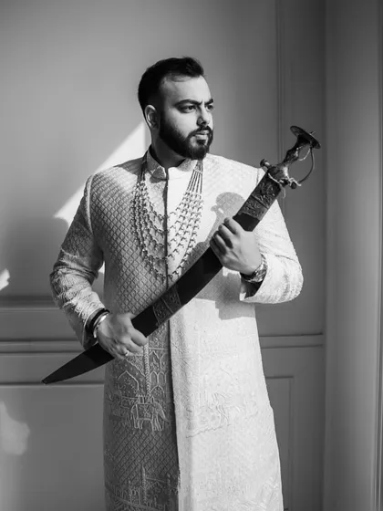 A groom's portrait is about capturing his strength and heritage. For Vikash, holding a family sword was a moment of pride and legacy. We use dramatic black and white photography to emphasize the emotion and timelessness of such traditions.