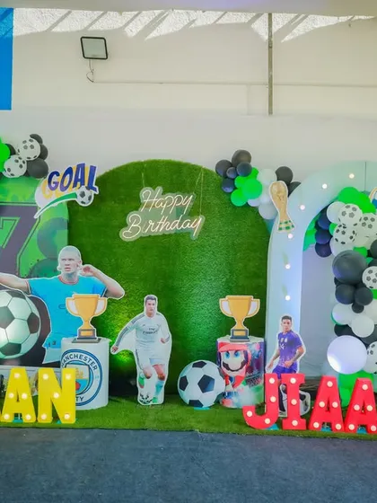 Another fantastic football theme setup for a joint birthday party. It features large light-up names, player cutouts, and a backdrop designed to look like a soccer field.