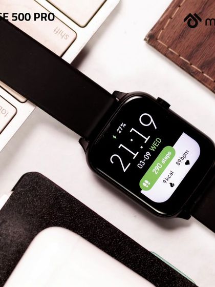 A close-up of the smartwatch on a desk, surrounded by a keyboard and other work essentials. This overhead shot highlights the watch's sleek design and clear, functional display.