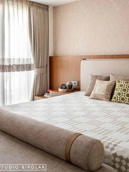 A close-up of the bedside, showing the beautiful texture of the wallpaper and the simple, clean lines of the furniture. The entire space is wrapped in soothing beiges and browns.