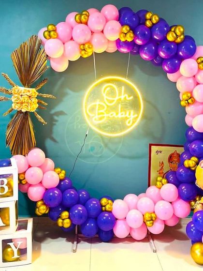 A bold and beautiful baby shower setup with a balloon ring in pink and purple. This decoration includes an 'Oh Baby' neon sign, 'BABY' blocks, and a baby-themed foil balloon for a complete look.