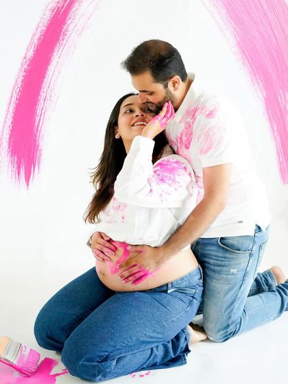 A joyful and messy moment from the paint reveal, with the couple kneeling together in a loving pose.