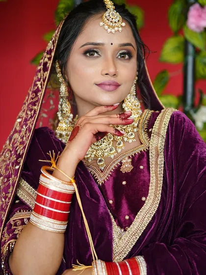 For this stunning North Indian bride, we created a glamorous look with bold, smoky eyes and a matte pink lip to complement her rich purple velvet lehenga. The heavy Kundan jewelry, chooda, and maang tikka complete this regal bridal ensemble.