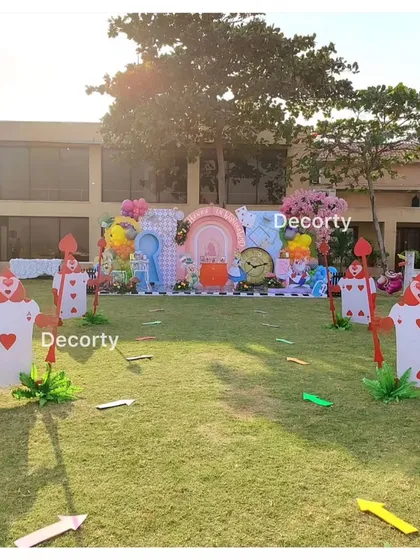 A wide view of the outdoor party space, with Queen of Hearts card soldiers lining the lawn.