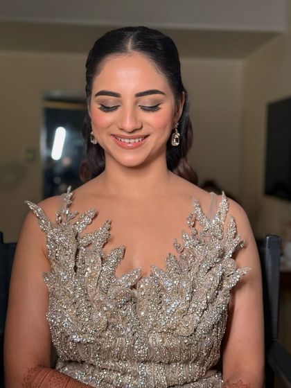 A beautiful portrait of a bride ready for her reception or cocktail party. The makeup is soft and glamorous, with a focus on glowing skin and shimmery eyes.