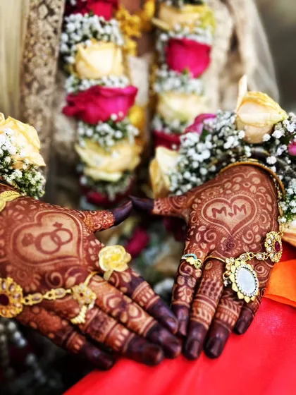 A beautiful engagement ceremony look, with the couple's initials 'MM' and interlocking rings drawn on the palms.