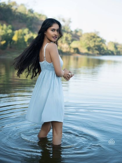 A candid moment from the lake shoot, with the model turning back with a smile. The ripples in the water and the natural light create a fresh and joyful image.