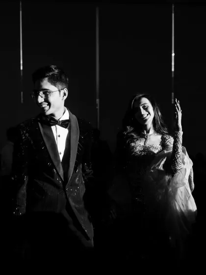A candid black and white shot of the couple laughing and dancing at their cocktail party, the high-contrast lighting adding to the drama.