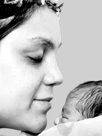 A close-up, artistic shot of a mother looking down at her newborn. The black and white edit adds a timeless, emotional quality.