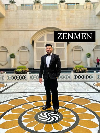 A full-length shot of me at an awards event, wearing a black tuxedo with abstract silver embroidery. The grand setting perfectly complements the sophisticated outfit.