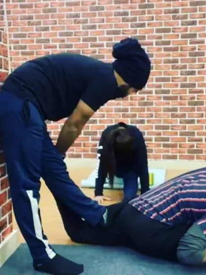 With the instructor's guidance, a student works on a deep hip-opening stretch, a key component for achieving full splits.
