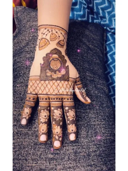 A close-up of a Karwa Chauth design featuring a 'jharokha' (window) with the couple's initials, surrounded by lotus patterns.