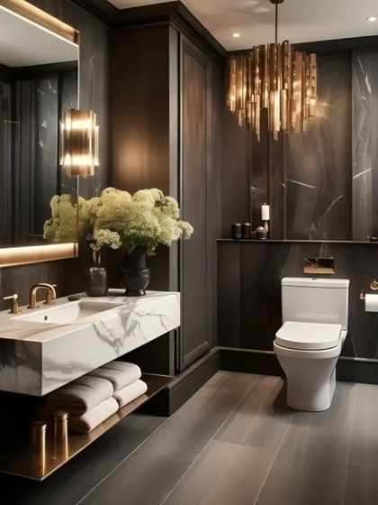 We created a dark and dramatic bathroom with this design. It features a floating marble vanity, a stunning modern chandelier, and gold-tone fixtures that contrast beautifully with the dark, textured walls.