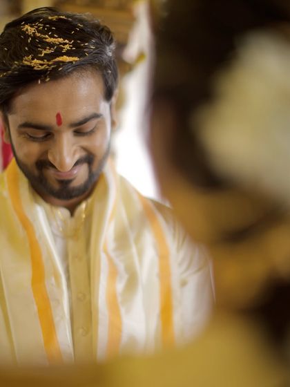 The groom's expression during a Kannada wedding ritual, full of shy smiles and happiness. We position ourselves to capture these fleeting, personal reactions that tell the emotional story of the day.