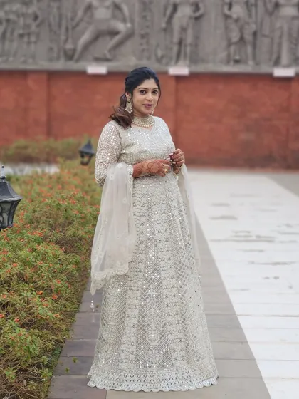 A full-length shot of the guest's elegant white outfit and polished makeup look.