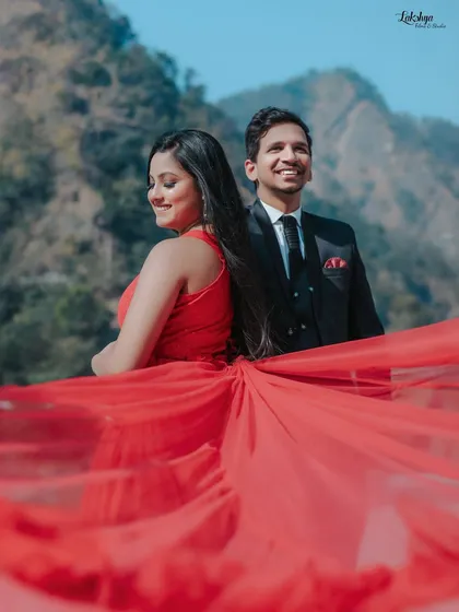 A dramatic shot with a flowing red gown against the mountainous backdrop of Rishikesh. Using props like long fabric trails adds a cinematic flair to outdoor shoots.