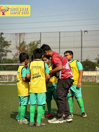 A coach speaks to a small group of young players in yellow bibs. We often break into smaller groups to provide more focused and personalized instruction.
