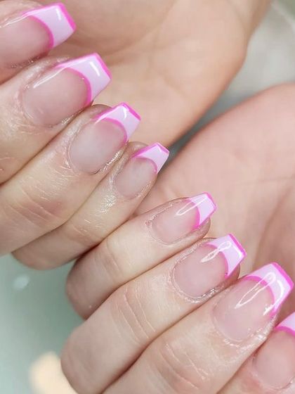 A modern French manicure with bright pink, angular tips on coffin-shaped nails for a bold and graphic look.