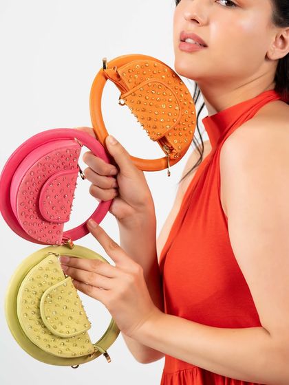 One bag, so many colours. A model holds three of my semi-circle mini bags, showing how these playful accessories can be the perfect finishing touch for a colourful and stylish look.