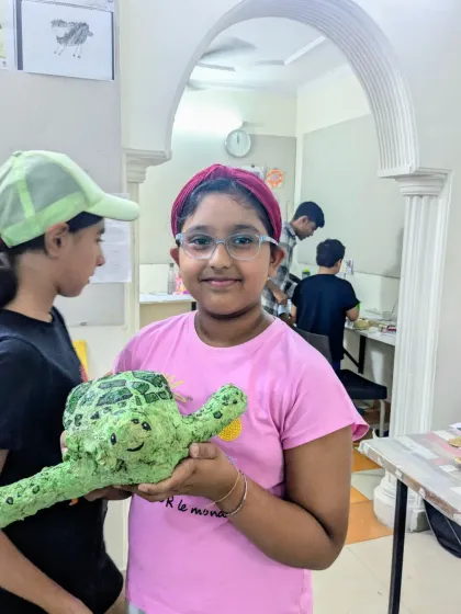 A close-up of a student with her fantastic green turtle sculpture. She did a great job with the texture and color, bringing her creature to life.