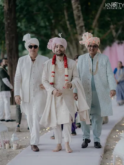 The groom's grand entrance at his Thailand beach wedding, flanked by his father and father-in-law. This shot captures the pride and emotion of the family as they walk down the aisle.