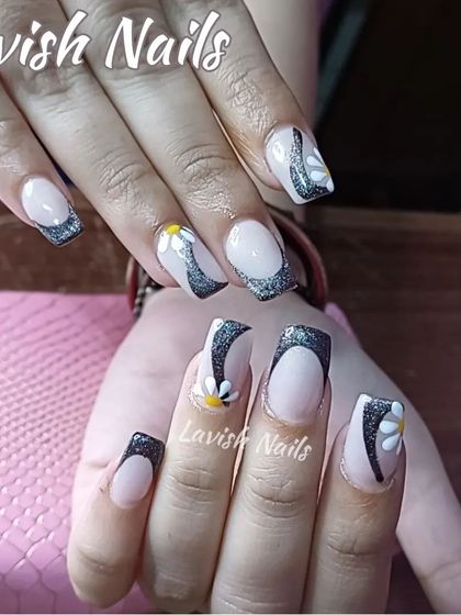 A playful design with black glitter French tips and hand-painted daisy accents.