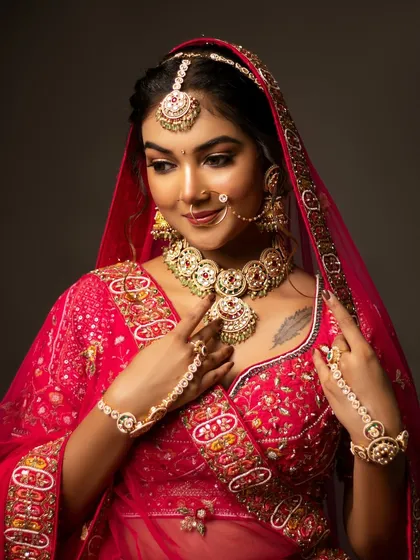 A mid-body shot of the bride in her stunning red lehenga, showing the intricate embroidery and jewellery.