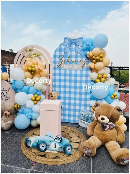 A closer look at the blue gingham teddy bear party backdrop, featuring a large plush bear and a vintage-style toy car.