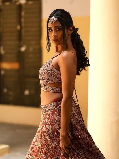 A side profile of Poornima, showing the details of her hairstyle and the beautiful silhouette of her outfit.