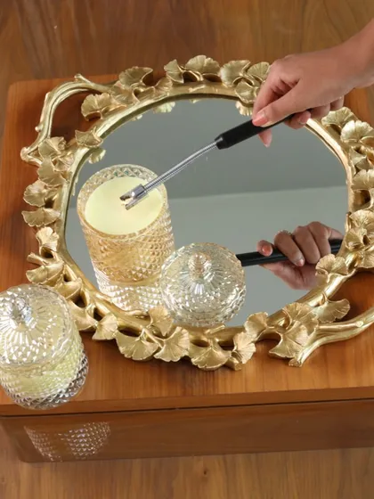 Our square ginkgo-leaf mirror tray, shown here with a candle being lit. The reflection in the mirror enhances the candlelight, creating a warm and inviting ambiance.