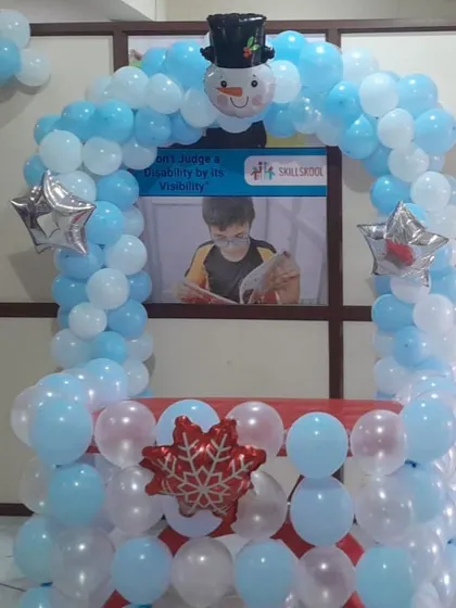 A clear, straight-on view of the winter-themed balloon booth, topped with a cute snowman foil balloon and accented with silver star balloons.