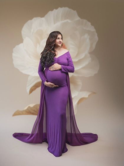 In this journey of motherhood, every moment is a blossom. This portrait, with its purple gown and delicate floral background, celebrates grace and strength.