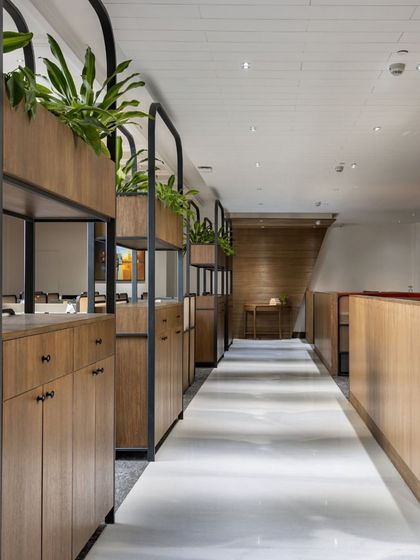 A detail of the custom partitions in the VRS Office, showing how they provide storage and a touch of green. The design uses natural oak and black metal for a look that is both modern and timeless.