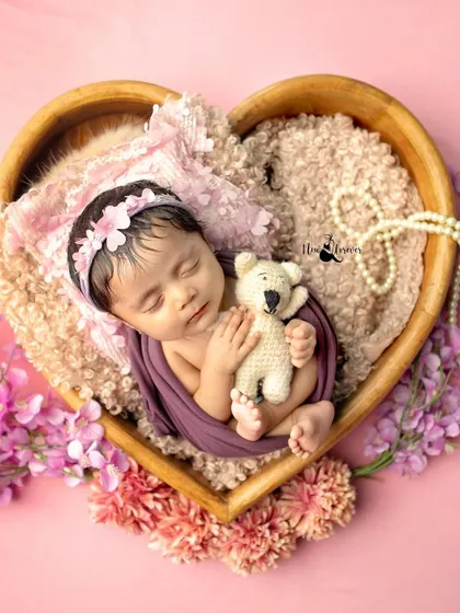 A newborn peacefully dreaming in a heart-shaped bowl, surrounded by soft pinks. This is the kind of timeless, gentle portrait I love to create in those magical first few days.