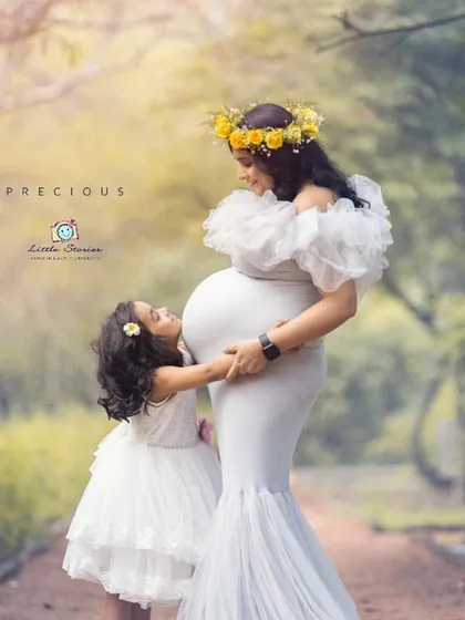 Welcoming a new baby is a special time for the whole family. In this outdoor maternity portrait, an older sister-to-be shares a precious moment with her mother, full of love and anticipation.