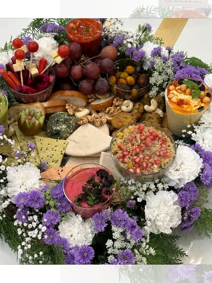 A breathtaking Mezze Platter nestled in a bed of fresh white and purple flowers. This presentation elevates the platter into a true work of art, perfect for luxury gifting or as a centerpiece.