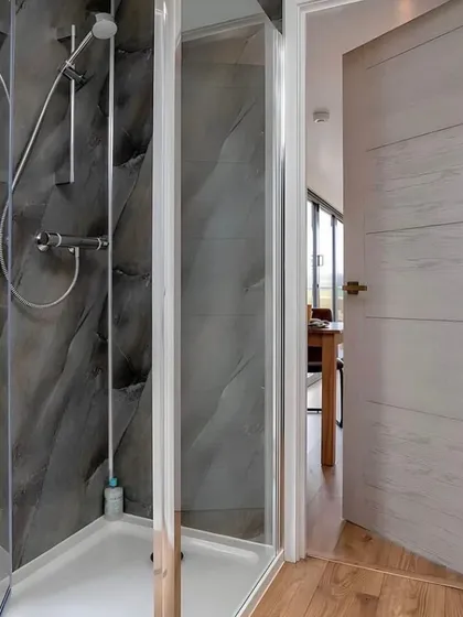 The bathroom in this container home features a modern glass shower with textured stone-like tiles, demonstrating our commitment to high-quality finishes even in compact spaces.
