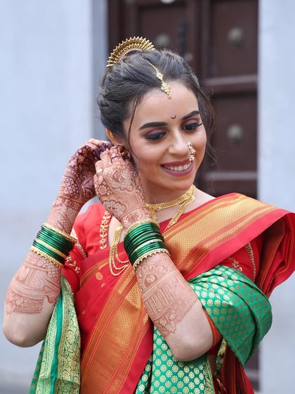 A candid moment of the bride getting ready. Her happy expression and the beautiful details of her attire, like the mundavalya and earrings, are perfectly captured.