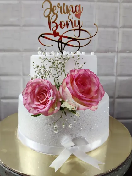 The final look of the two-tier anniversary cake, featuring a custom topper with the couple's names, Jerina and Bony.